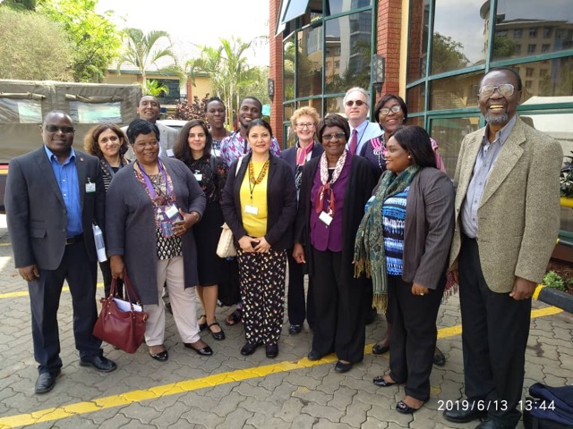 Side-shot of civil society representatives, seated at a long table in plenary, looking towards the camera and smiling..