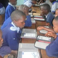 Children in a classroom reading with the e-readers. 