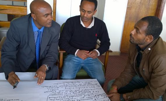 Three men discussing the Open Access indoors