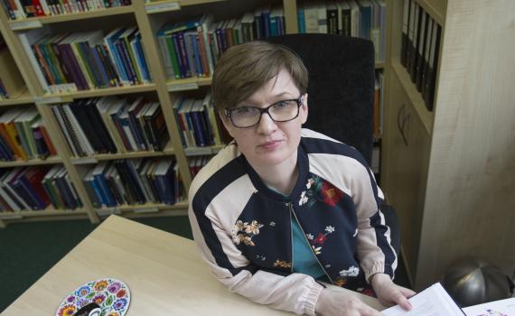 EIFL Copyright Coordinator in Poland, Barbara Szczepańska, sitting at her desk, with bookshelves in the background. 