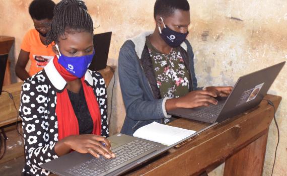 Two young women learning computer skills in a Ugandan public library.